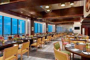 a dining room with tables and chairs and windows at The Westin Kolkata Rajarhat in Kolkata