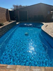 una piscina de agua azul frente a un edificio en Clock Tower Motor Inn, en Coonabarabran