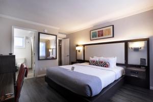 パロアルトにあるザ パロ アルト インの大きなベッドと鏡が備わるホテルルームです。
