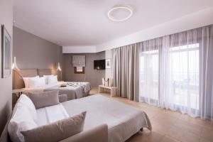 a hotel room with two beds and a large window at Olympion Sunset Halkidiki in Fourka
