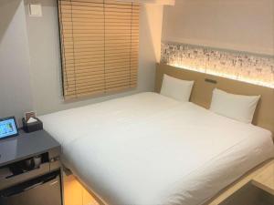 uma grande cama branca num quarto com uma janela em HOTEL AMANEK Kamata-Eki Mae em Tóquio