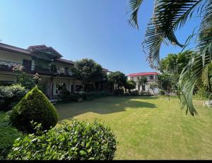 a yard in front of a house with a palm tree at Karans Corbett Motel in Rāmnagar +12 photos