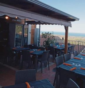 een restaurant met blauwe tafels en stoelen en de oceaan bij Sognando nel borgo in Rocca Imperiale