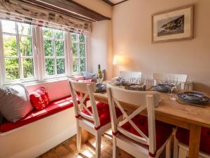 uma sala de jantar com mesa, cadeiras e janelas em Hope Cottage em Beer