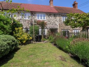 une vieille maison en pierre avec un jardin devant dans l'établissement Hope Cottage, à Beer