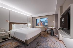北京市にあるSunworld Dynasty Hotel Beijing Wangfujingのベッドとテレビが備わるホテルルームです。