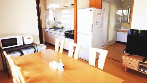 a kitchen with a wooden table and a refrigerator at さつきあん in Miyako Island