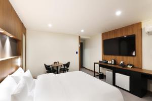 ein Hotelzimmer mit einem Bett und einem TV in der Unterkunft Jeonju Urban Hotel in Jeonju