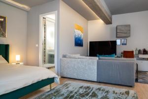 ボローニャにあるPiazza Maggiore Santa Margherita b&bのベッドルーム(ベッド1台、ソファ、テレビ付)