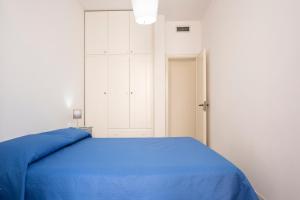 1 dormitorio con cama azul y puerta blanca en Appartamento Cortese, en San Vito lo Capo