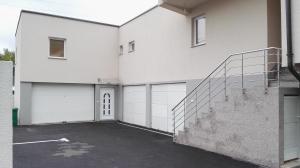 a white house with two garage doors and a staircase at Apartments Foco in Sarajevo