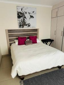 um quarto com uma grande cama branca com almofadas vermelhas em E & P Cave em Swakopmund