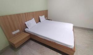 uma cama com lençóis brancos e almofadas num quarto em FabHotel Park Mahindra em Raipur