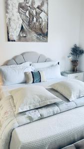 1 cama con almohadas blancas y una pintura en la pared en La ROMANTICA VERONA, en Verona