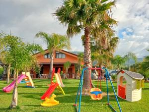 un parque infantil frente a una casa con palmeras en B&B Villa Molinari, en Campagna