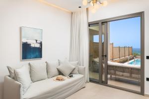 a living room with a white couch and a sliding glass door at Diamond Star Hotel in Falasarna