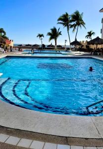 ein großer blauer Pool mit Palmen im Hintergrund in der Unterkunft Quintas del mar Mazatlán in Mazatlán