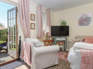 ein Wohnzimmer mit 2 weißen Stühlen und einem TV in der Unterkunft Sunset Cottage in Barnstaple