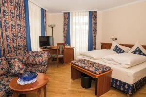 Habitación de hotel con cama y sofá en Moselland Hotel im Enderttal Zum Onkel Willi, en Cochem