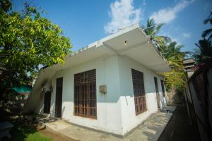 a white house with wooden doors and a fence at koggala House By The Rock in Habaraduwa