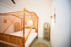 a bedroom with a wooden canopy bed and a shelf at koggala House By The Rock in Habaraduwa