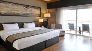 a hotel room with a large bed and a balcony at Jpark Island Resort & Waterpark Cebu in Mactan