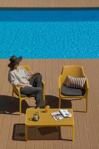 Hotel Saltic Resort & Spa Grzybowo في كولوبرزيغ: رجل جالس في كراسي بجانب مسبح
