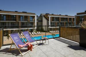 a couple of lounge chairs on a balcony with a pool at Hotel Saltic Resort & Spa Grzybowo in Kołobrzeg