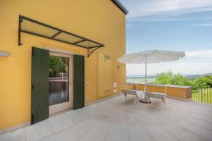 um pátio com um guarda-sol, uma mesa e cadeiras em La Rubiana Apartment em Caprino Veronese