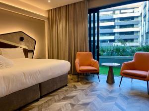 una camera d'albergo con un letto e due sedie di Coastlands Skye Hotel, Ridgeside, Umhlanga a Durban