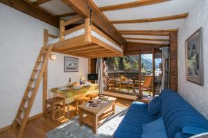 un soggiorno con divano blu e letto a soppalco di Résidence Améthystes D12 ski in ski out - Happy Rentals a Chamonix-Mont-Blanc
