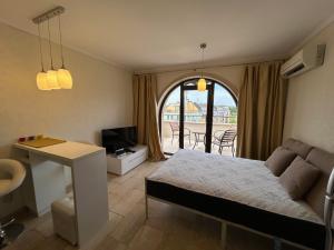 a bedroom with a bed and a desk and a television at Apartments Amara Sunny Beach in Sunny Beach