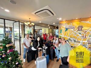 a group of people standing in a lobby with luggage at Siri Oriental Bangkok Hotel in Bangkok