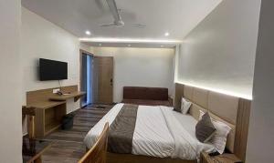 a bedroom with a bed and a desk and a television at FabHotel Prakash in Ujjain