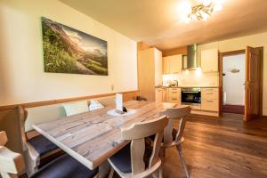 uma cozinha e sala de jantar com uma mesa de madeira e cadeiras em Oberlehenhof em Kaprun