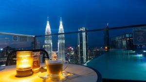 a glass of beer sitting on a table with a city skyline at Imperial Luxury Suites KLCC by Moonway in Kuala Lumpur