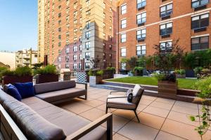 a patio with a couch and chairs and buildings at City Views Penthouse NYC in 5min in Hoboken
