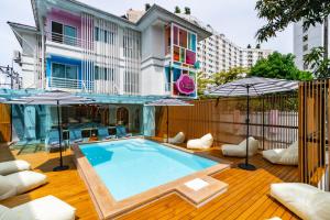 プーケットタウンにあるThe Tint At Phuket Town - SHA Plusの木製デッキのパラソル付きスイミングプール
