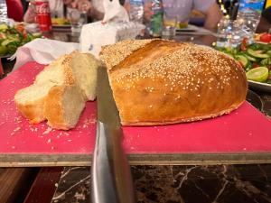 a loaf of bread on a red cutting board with a knife at Deep Ashri Star House Hotel in Marsa Alam City
