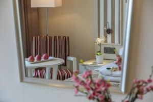 a mirror reflecting a living room with a table and a chair at Aquamare Beach Hotel & Spa in Paphos City