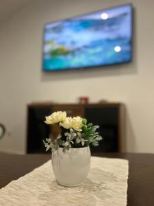a white vase with flowers sitting on a table at Apartman Diamond LUX in Surčin