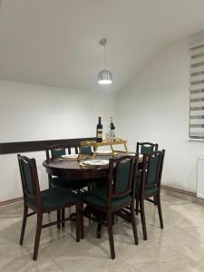 Apartman Diamond Lux في Surčin: طاولة غرفة طعام مع كراسي وزجاجة من النبيذ