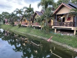dom obok rzeki z palmami w obiekcie Khao Yai Lake Hill Resort เขาใหญ่เลค ฮิลล์ รีสอร์ท w mieście Khanong Phra