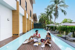 a man and a woman sitting next to a swimming pool at Book a Bed Poshtel - SHA Plus in Phuket +239 photos
