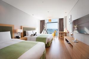 a hotel room with two beds and a large window at Hidden Bay Hotel in Yeosu