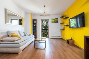 a living room with a couch and a yellow wall at Apartmány Jako doma in Plzeň