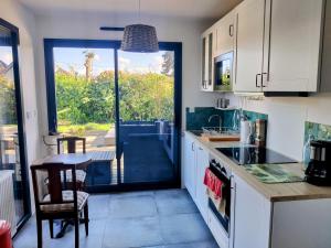 eine Küche mit weißen Schränken und Blick auf einen Hof in der Unterkunft RARE à Cabourg - Maison neuve avec piscine et jardin in Cabourg