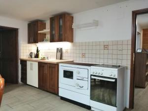 a kitchen with white appliances and wooden cabinets at Rajecká chata in Rajecká Lesná