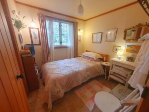 a bedroom with a bed and a table and a window at Bumblebee Cottage in Greytown
