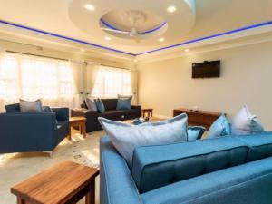 sala de estar con sofás azules y TV en The Shrub Lodge en Victoria Falls